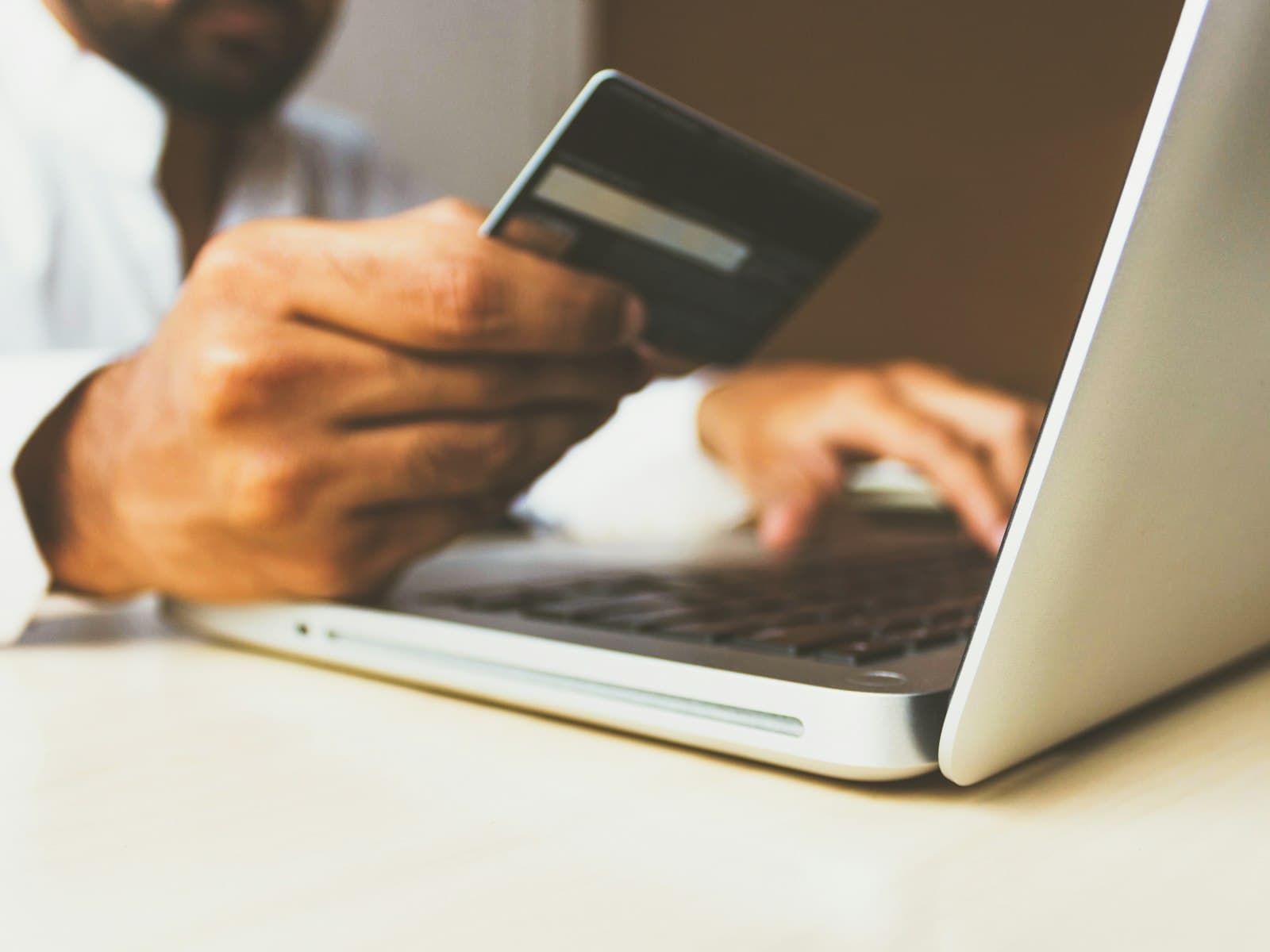 Person holding a credit card while working at a laptop